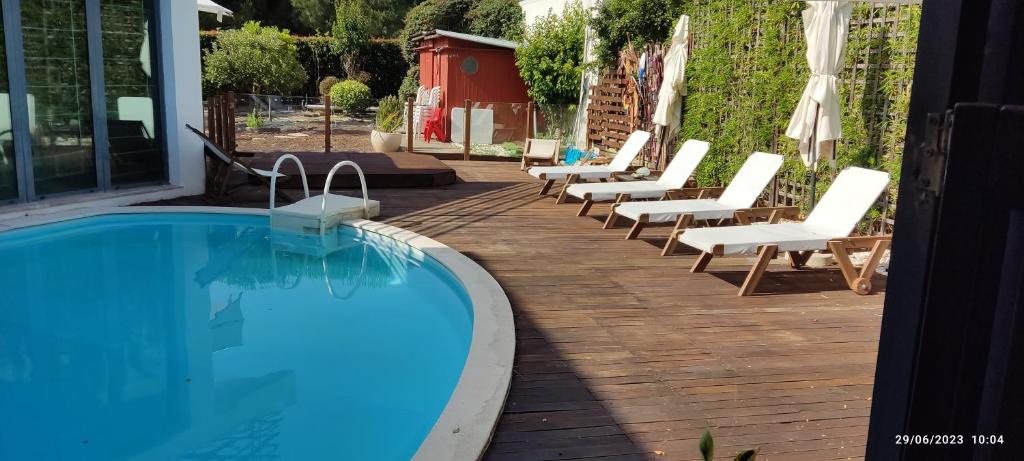 a row of lounge chairs and a swimming pool at Villa De Lux with pool in Quinta do Anjo