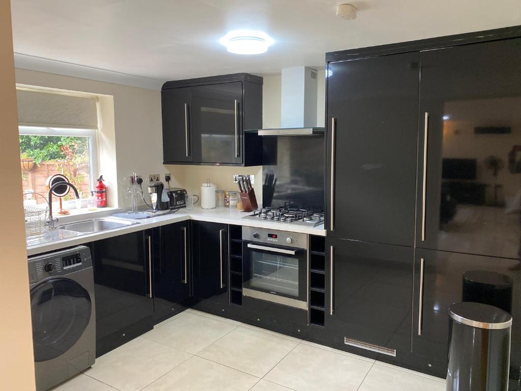 a kitchen with black cabinets and a stove top oven at Studio flat Gants Hill with Free Parking in Redbridge