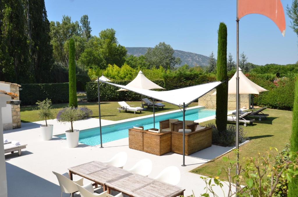 een tuin met een zwembad en witte parasols bij maison bertuli Oliviers Aircon, heated saltwater Pool, 2 Bedrooms in Oppède