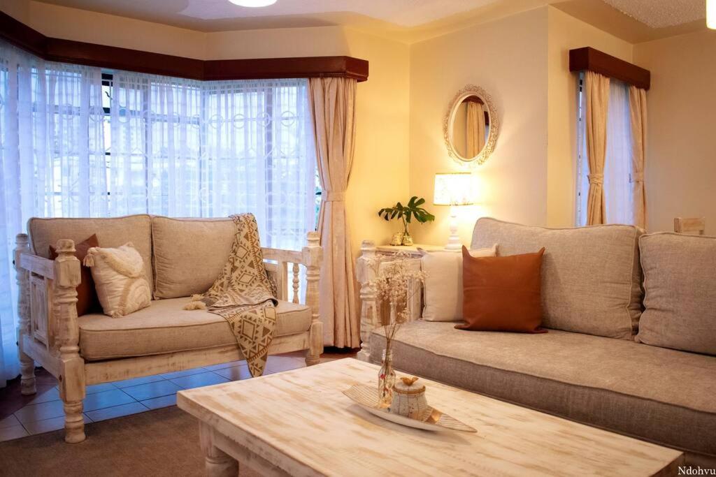 a living room with two couches and a coffee table at Warm & Cozy 2-Br Apartment. 10 mins from City Centre in Nairobi
