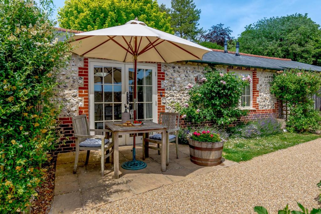 a table with an umbrella in front of a house at Hop Cottage in East Dean