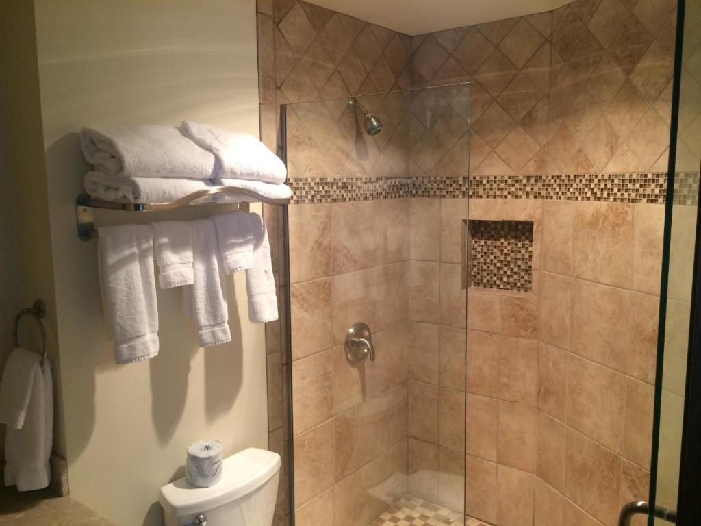 ein Bad mit einer Dusche, einem WC und Handtüchern in der Unterkunft Candlestone Golf and Resort in Belding