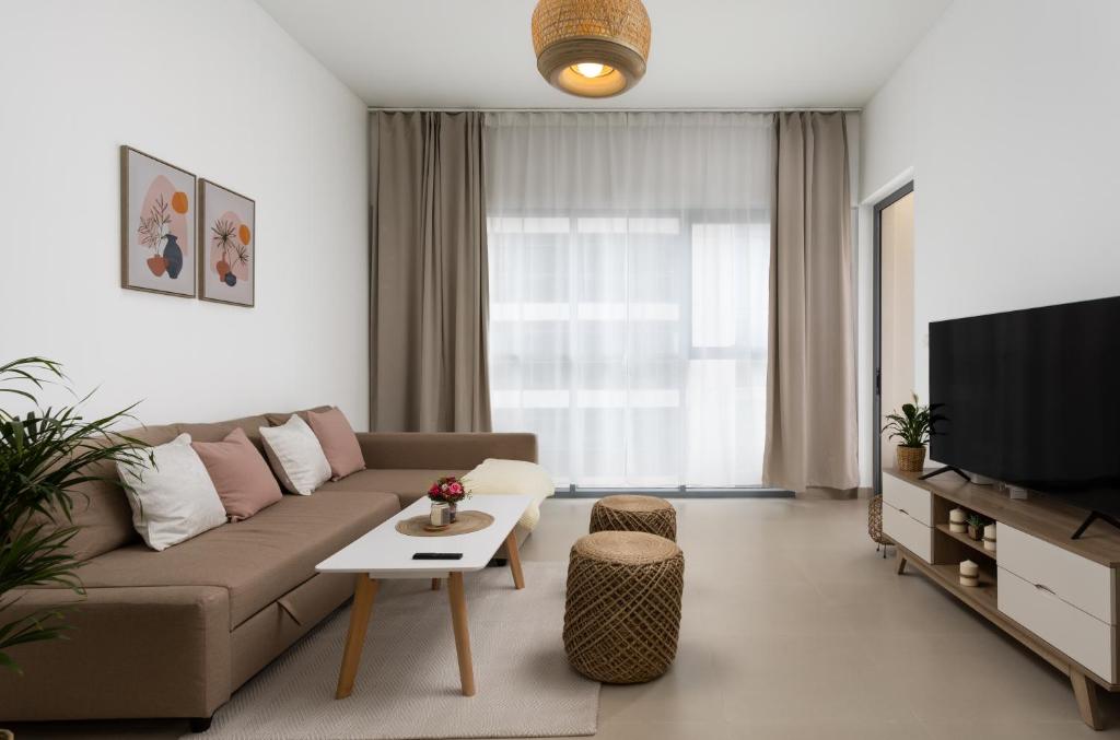 uma sala de estar com um sofá e uma televisão em Waves Holiday Home - Chic Apartment With Dubai Skyline Views no Dubai