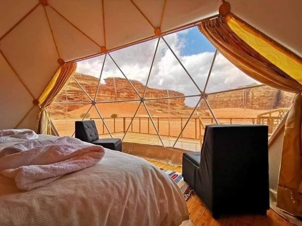 a tent with a bed and a view of the desert at Wadi Rum Gulf camp in Aqaba