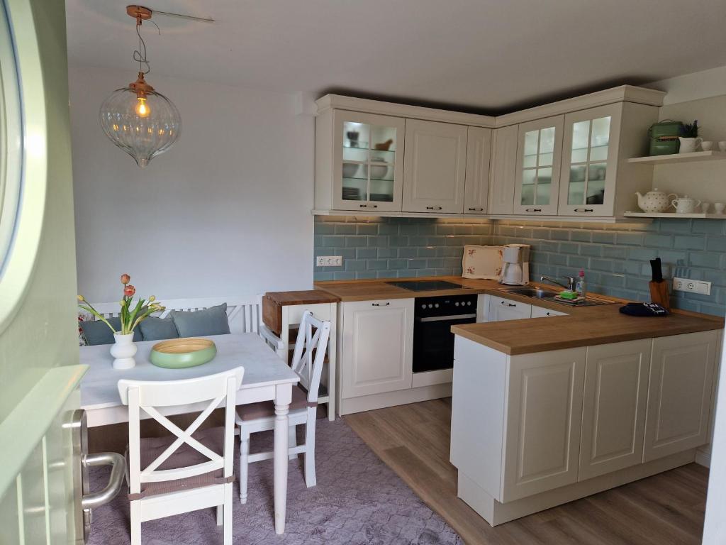 a kitchen with white cabinets and a table with chairs at Ferienwohnung Düne mit Kamin und 2 Bädern in Boltenhagen in Boltenhagen