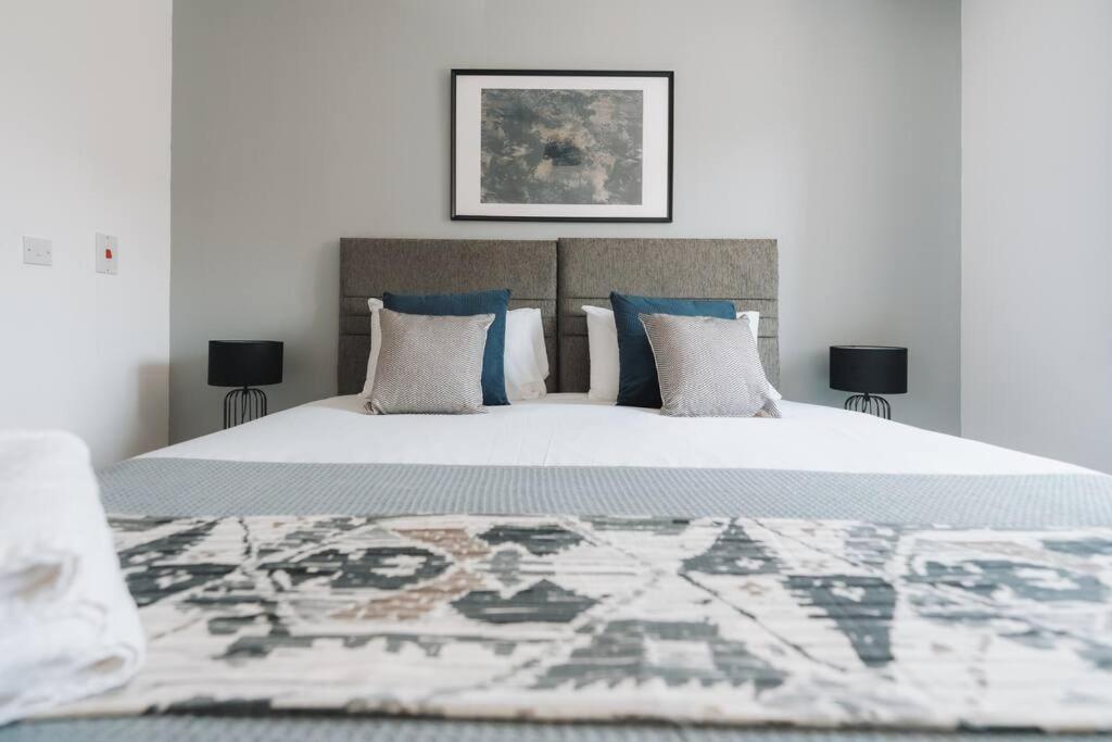 een slaapkamer met een groot wit bed met blauwe kussens bij Hoskins House By Horizon Stays in Middlesbrough