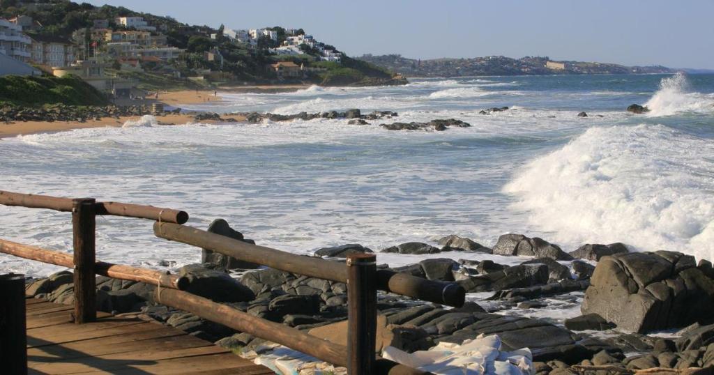 a view of a beach with waves and rocks at Dolphin Coast Getaway in Ballito