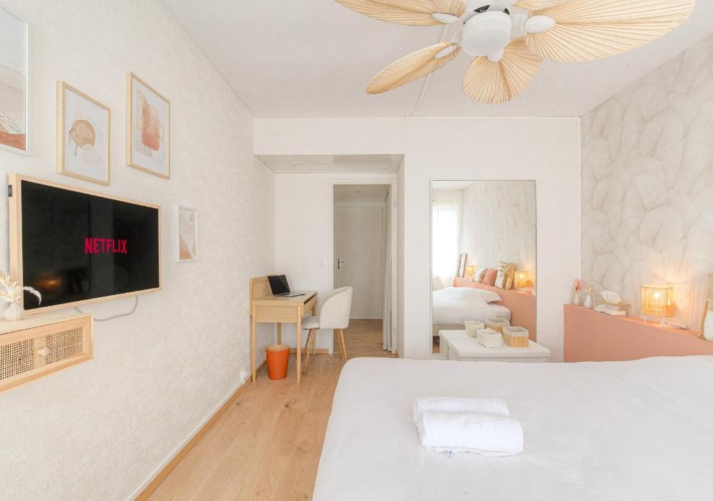 a white bedroom with a bed and a ceiling fan at LOUISE - Studio de qualité et très cozy in Saint-Étienne