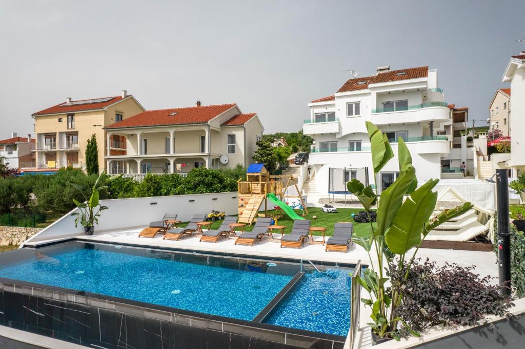 a swimming pool with chaise lounge chairs next to a house at Holiday House Dominik apartments in Sveti Petar