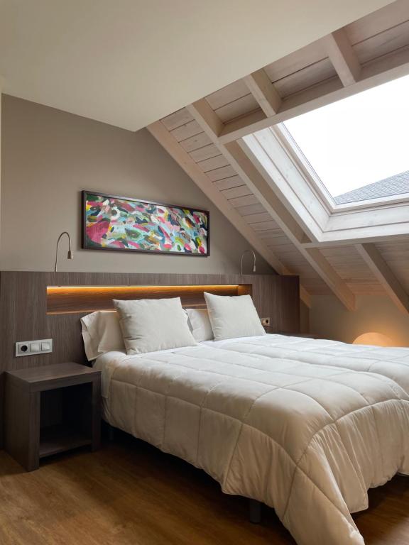 a bedroom with a large white bed with a skylight at Guiana Rooms - Adults Only in Ponferrada