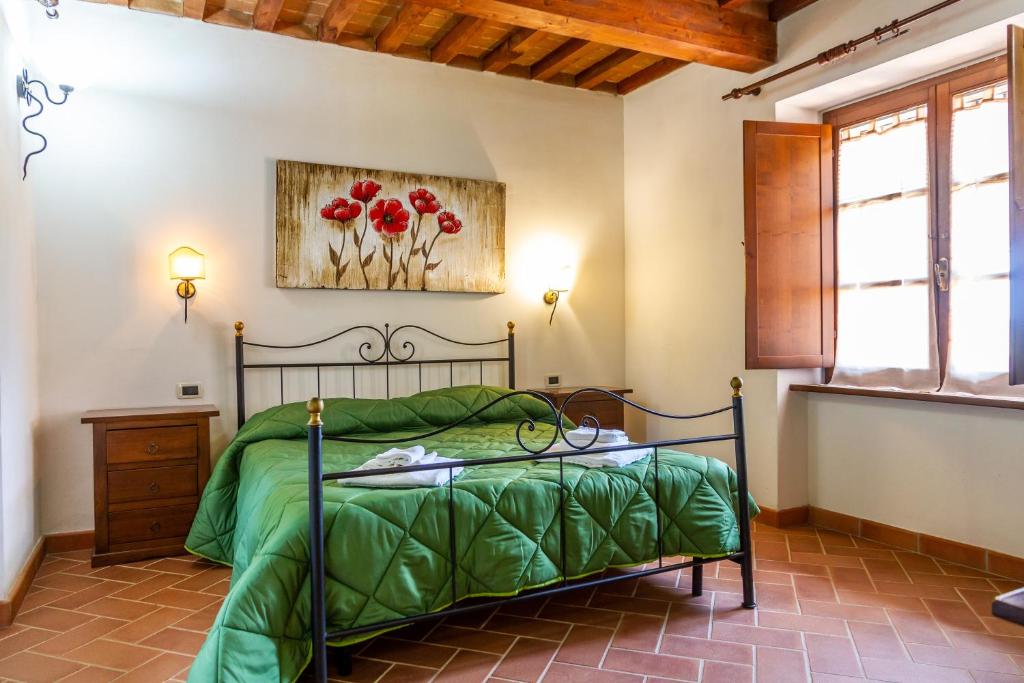 a bedroom with a bed with a green comforter at Casa Vacanza Il Carpignone 2 in Massa Marittima