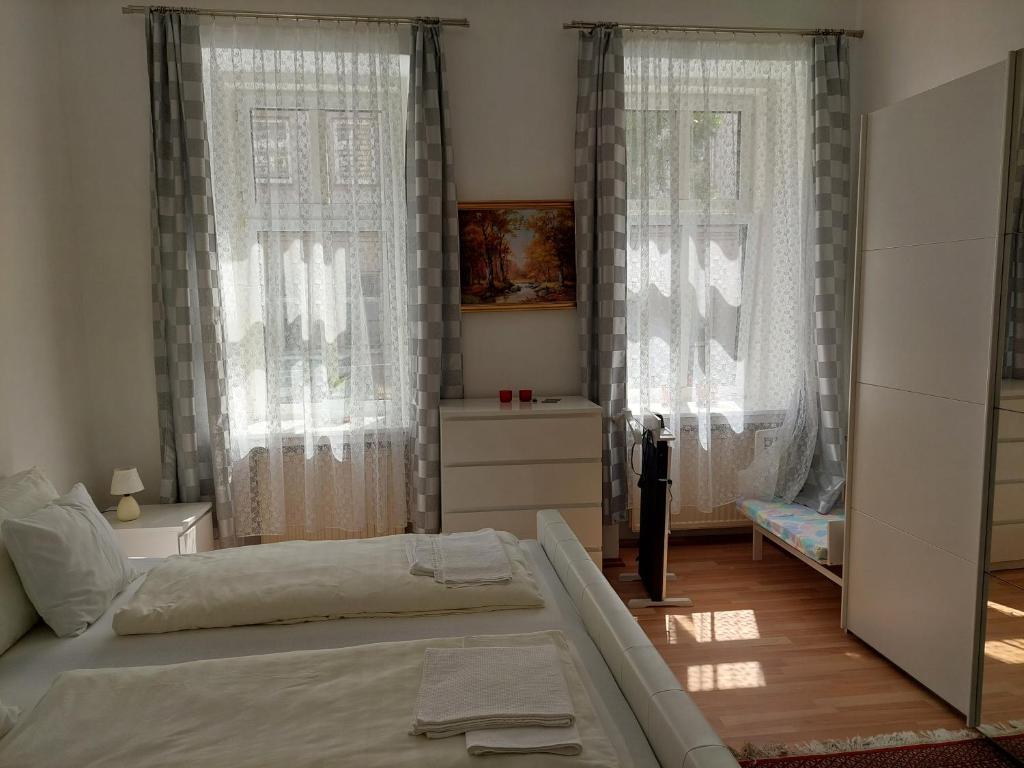ein Schlafzimmer mit zwei Betten und zwei Fenstern in der Unterkunft Weißes Appartement in Wien