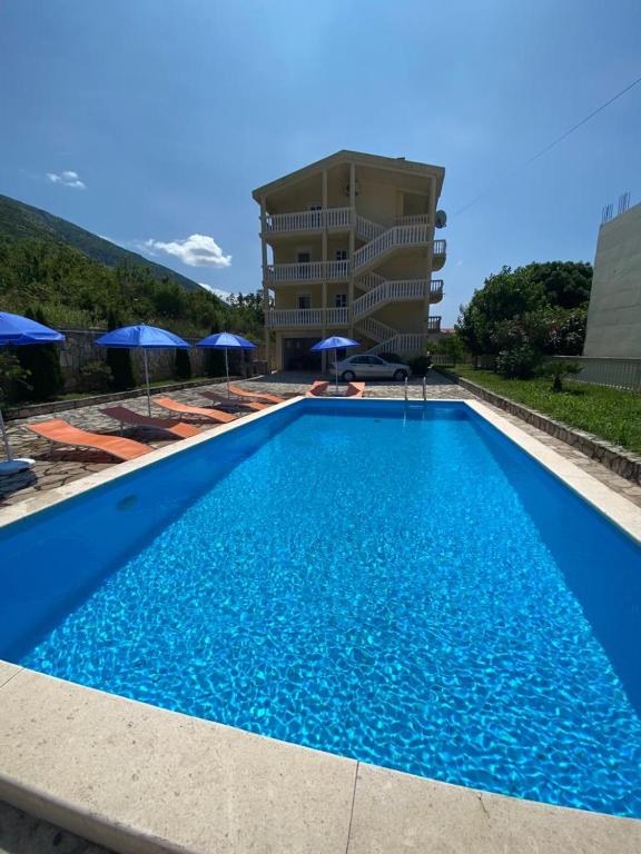 a large blue swimming pool with umbrellas and a building at Romantic auch mit Kindern in Sutomore