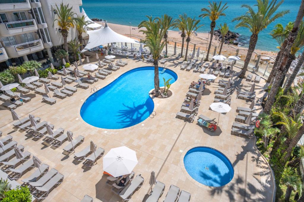 Caprici Beach Hotel & Spa في سانتا سوزانا: إطلالة علوية على مسبح وكراسي والشاطئ