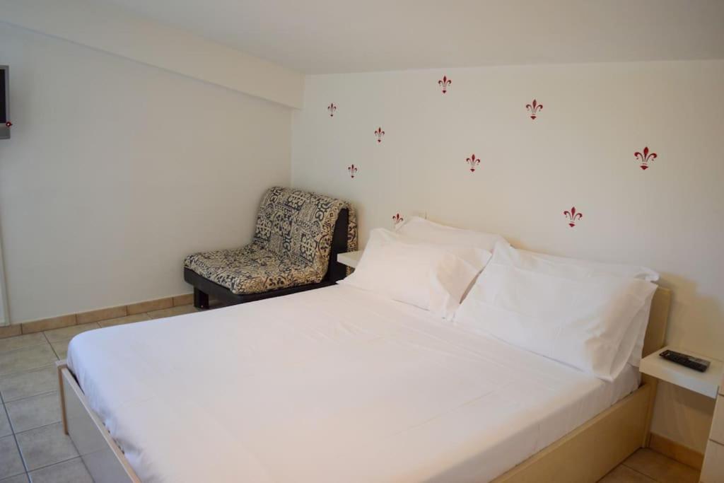 1 dormitorio con 1 cama blanca y 1 silla en Homiday - Tamerici Attico, en Pineto