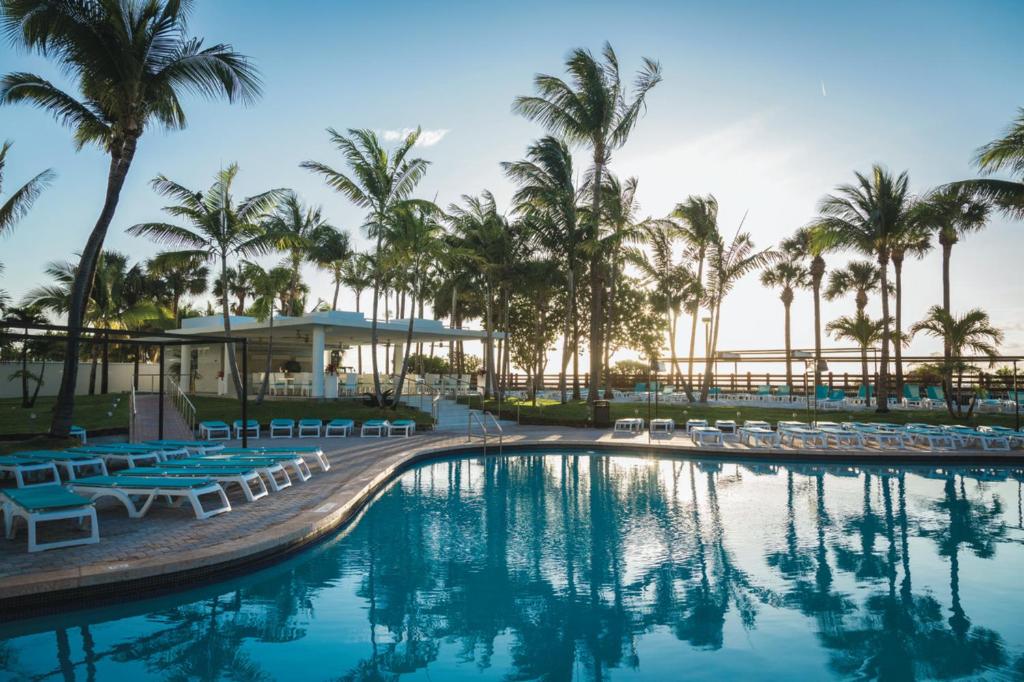 einen Pool in einem Resort mit Stühlen und Palmen in der Unterkunft Riu Plaza Miami Beach in Miami Beach