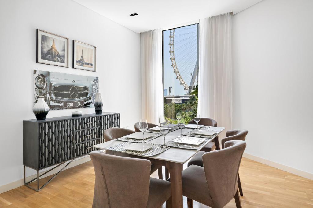 a dining room with a table and chairs and a large window at VayK - Spacious One Bedroom with Ain Views in Dubai