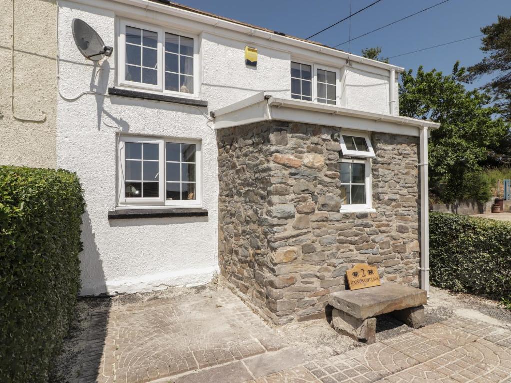 una casa de piedra con un banco delante en Daisys Cottage, en Burry Port