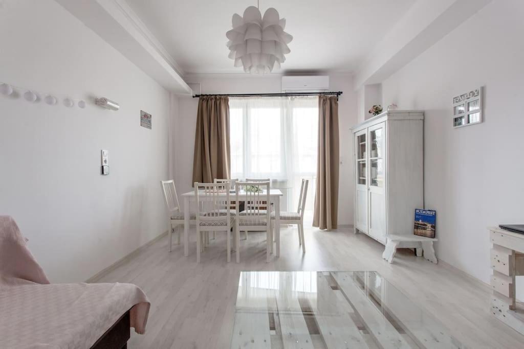 Brand new, large apartment with opening discount في بودابست: غرفة معيشة بيضاء مع طاولة وغرفة طعام