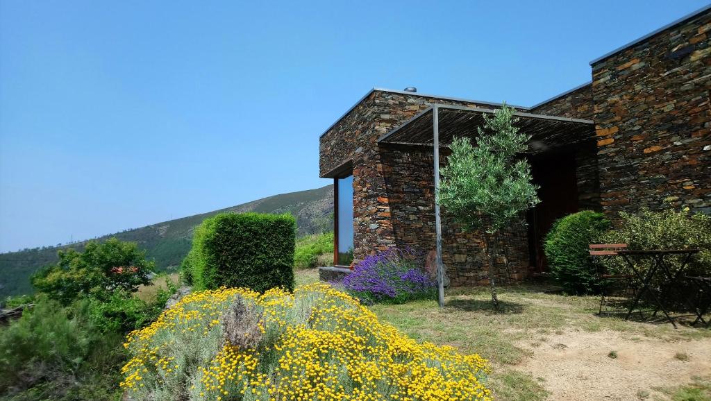 a stone building with flowers in front of it at InXisto Lodges in Piódão