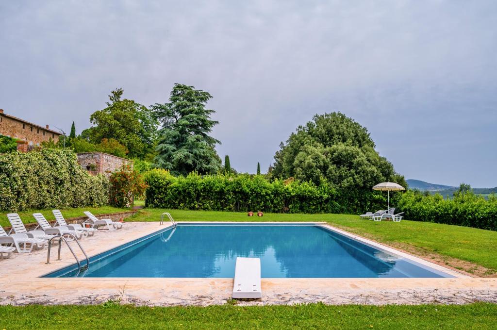 una piscina in un cortile con sedie e ombrellone di La Serra Vitignano-Stunning Villa W/Swimming Pool! a Castelnuovo Berardenga