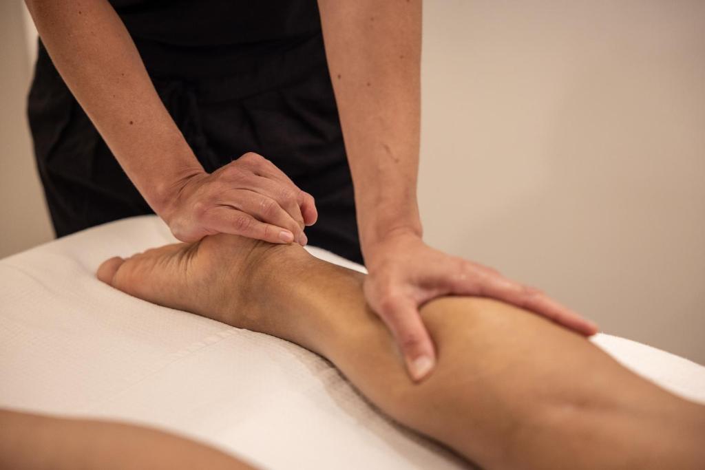Eine Frau bekommt eine Fußmassage von einem Massagetherapeuten. in der Unterkunft Hôtel &amp; Espace Bien-être La Maison du Lierre in Biarritz