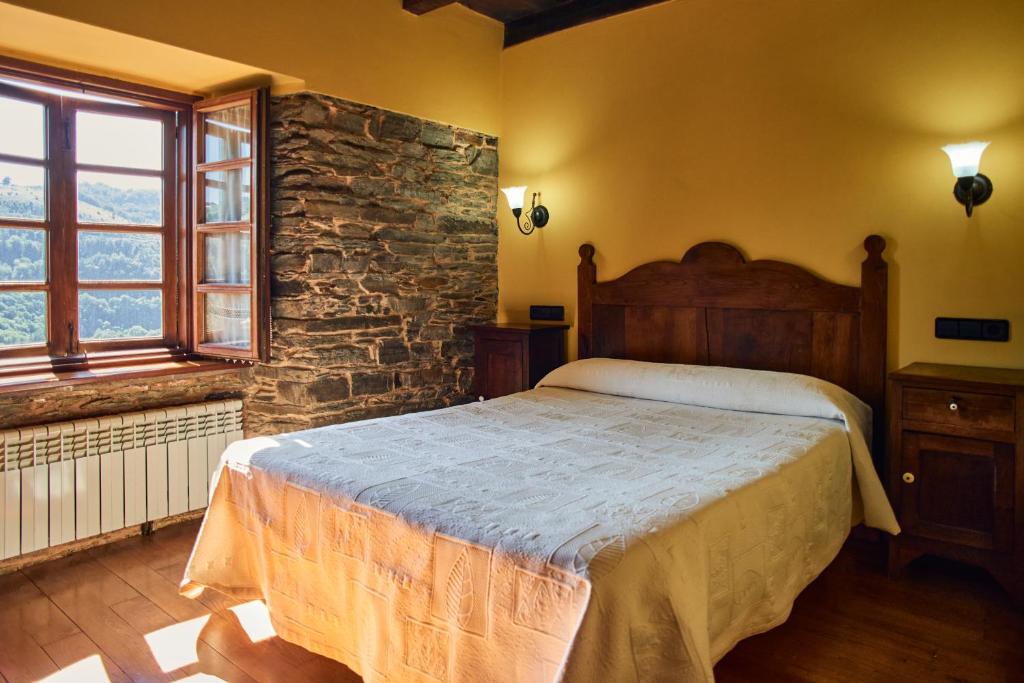 1 dormitorio con cama y pared de piedra en A Casoa, en Santa Eulalia de Oscos
