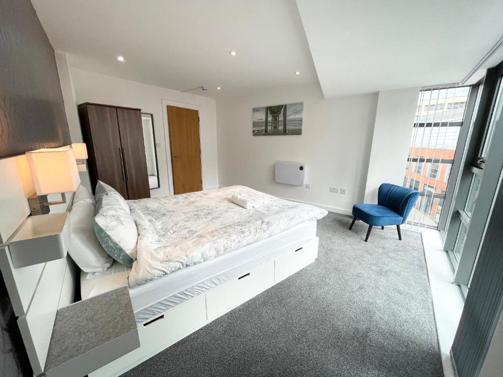 a bedroom with a bed and a blue chair at The Works-Fresh 2bed in centre, opposite Arndale. in Manchester