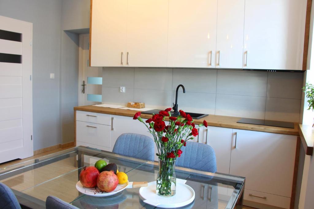 kuchnia ze szklanym stołem z wazonem kwiatów w obiekcie APART MAZURY Apartamenty na Mazurach w Orzyszu