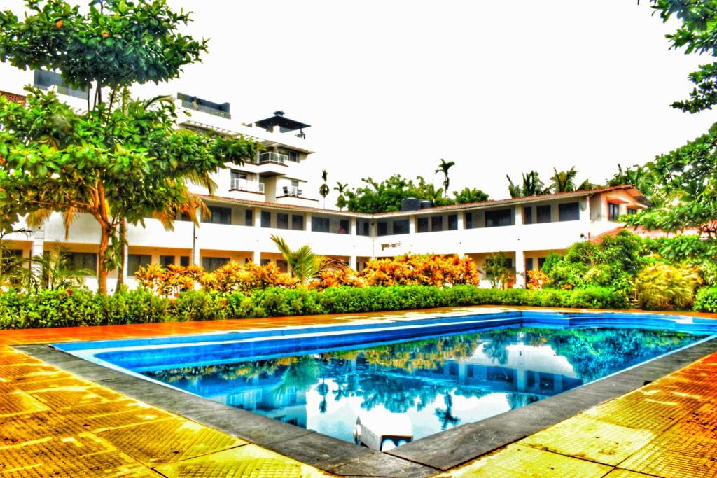 a swimming pool in front of a building at Opulence Beach Resort Awas, Alibaug in Alibaug