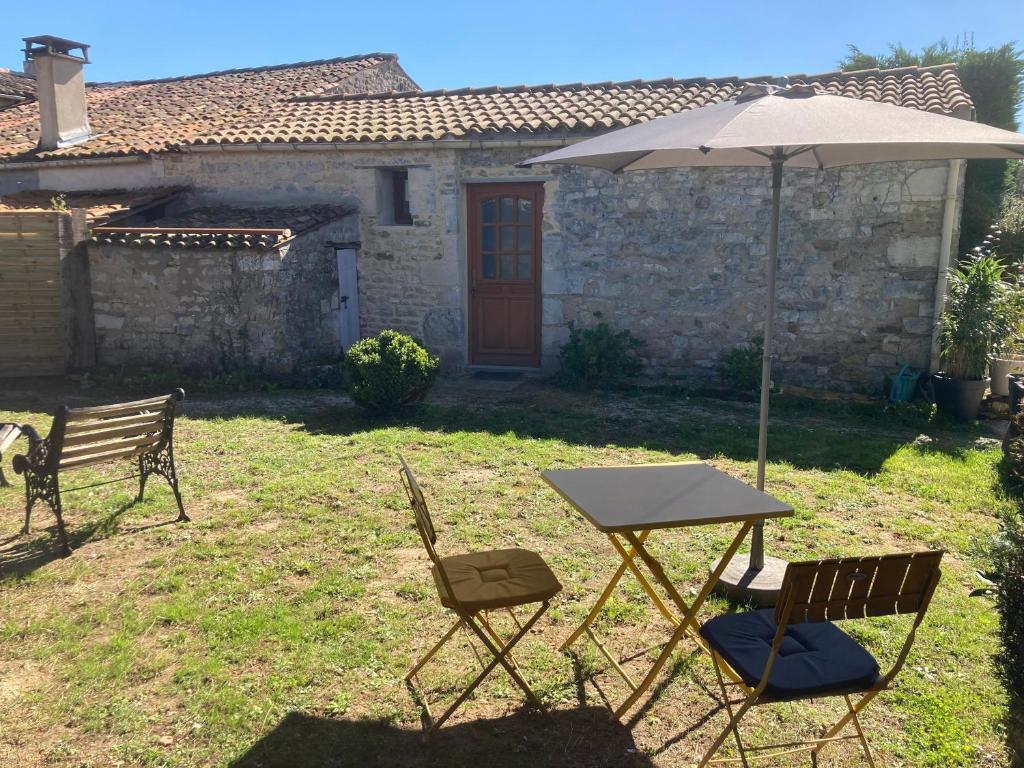 a table and two chairs and an umbrella in a yard at LES ROCHES gîte in Corme-Royal