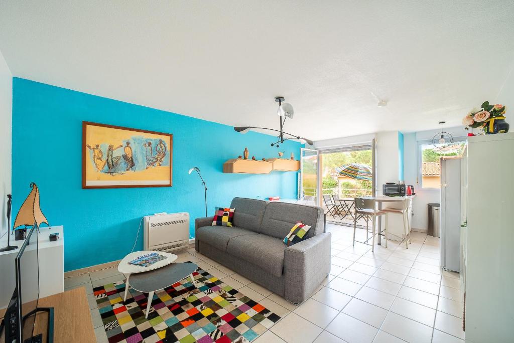 un soggiorno con divano e parete blu di La Casa de Cricri - Appartement climatisé a Perpignano