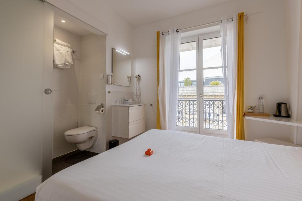 a bedroom with a bed and a toilet and a window at Hôtel & Espace Bien-être La Maison du Lierre in Biarritz