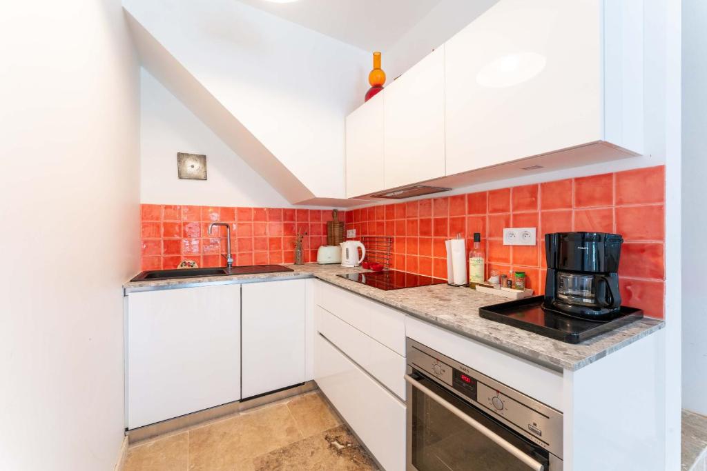 una cocina con armarios blancos y azulejos rojos en Mas du Petit Duc, en Cavaillon