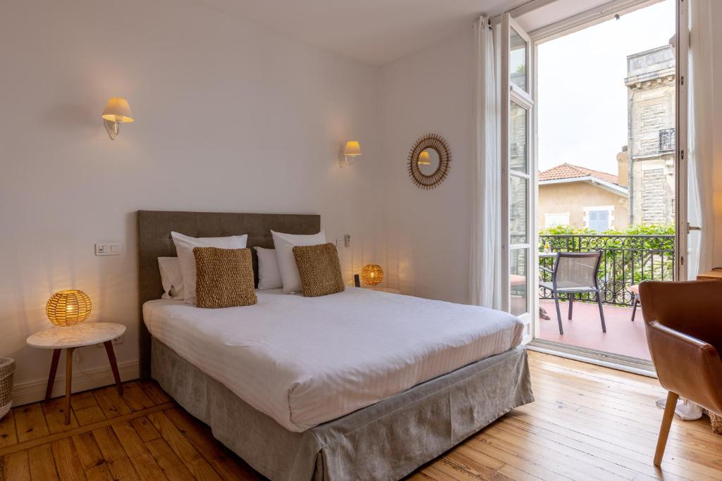 ein Schlafzimmer mit einem Bett und einem großen Fenster in der Unterkunft Hôtel &amp; Espace Bien-être La Maison du Lierre in Biarritz