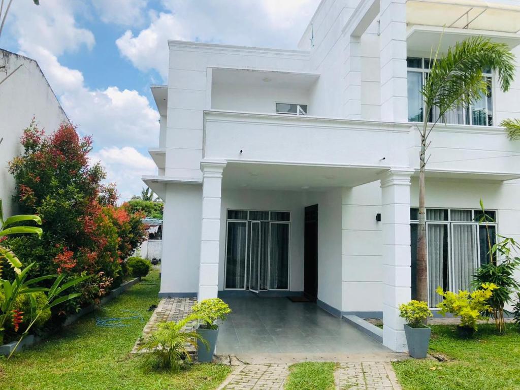 a white house with plants in front of it at Vidushi Home in Minuwangoda