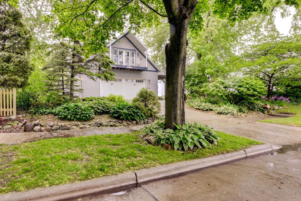 a house with a tree in front of a street at Sheboygan Getaway with Deck and On-Site Lake Access! in Sheboygan
