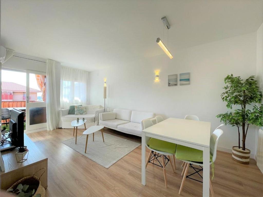 uma sala de estar com um sofá branco e uma mesa em Apartamento Con Piscina y Gran Terraza con Vistas - Muy cerca de la playa, el centro y la estación em Vilassar de Mar