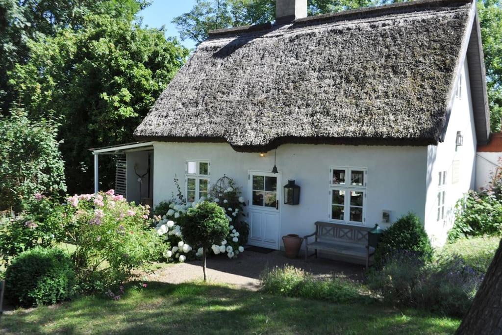 um pequeno chalé branco com um telhado de palha em Zauberhaftes englisches Cottage am Gutshaus em Groß Schoritz