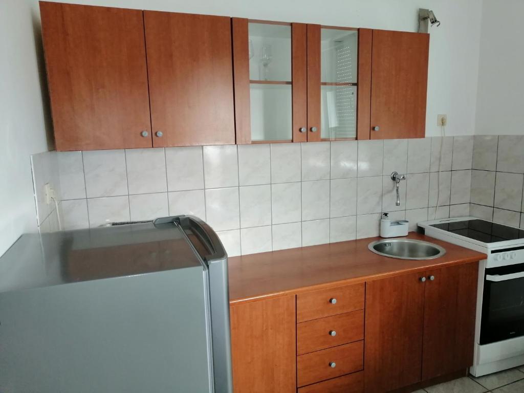 a kitchen with wooden cabinets and a sink and a refrigerator at Studio apartman Laca in Šibenik