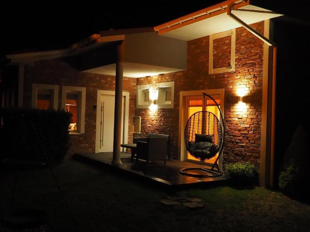 a house with a patio at night with a wicker chair at Pod Morskim Niebem in Poddąbie