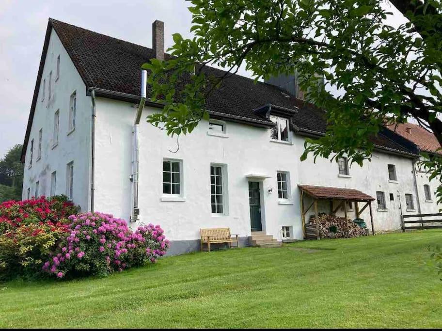 ein weißes Haus mit einer Bank im Hof in der Unterkunft Landidylle auf dem Rittergut in Blomberg