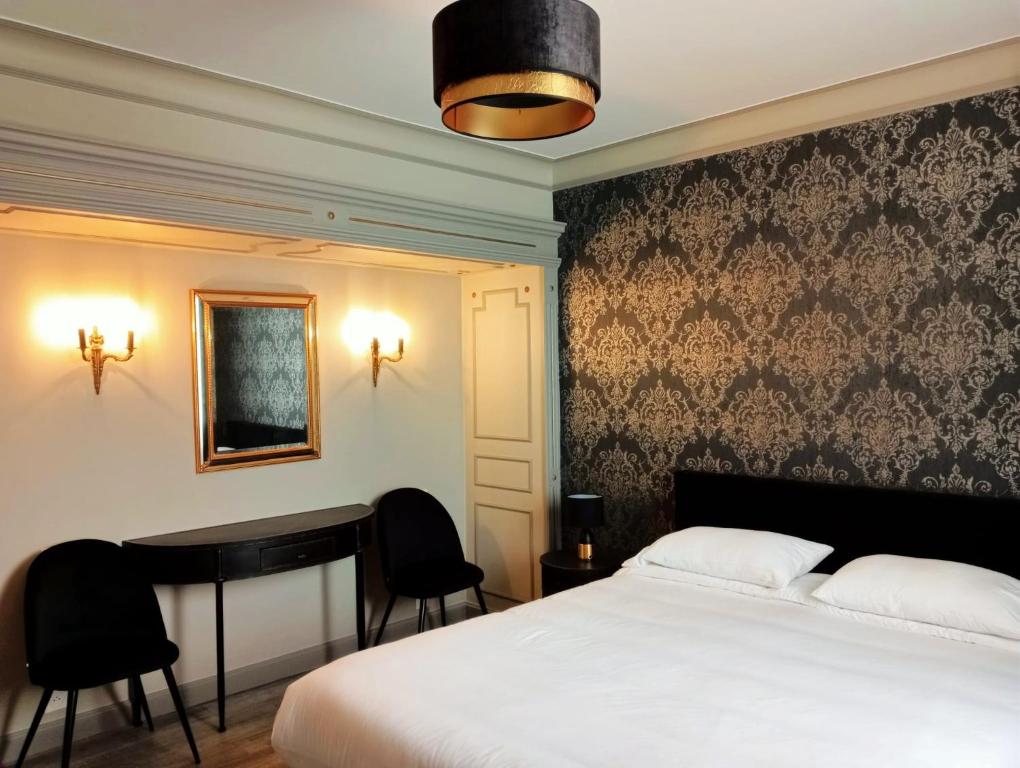 a bedroom with a bed and a desk and a table at La Villa Perigourdine in Sarlat-la-Canéda