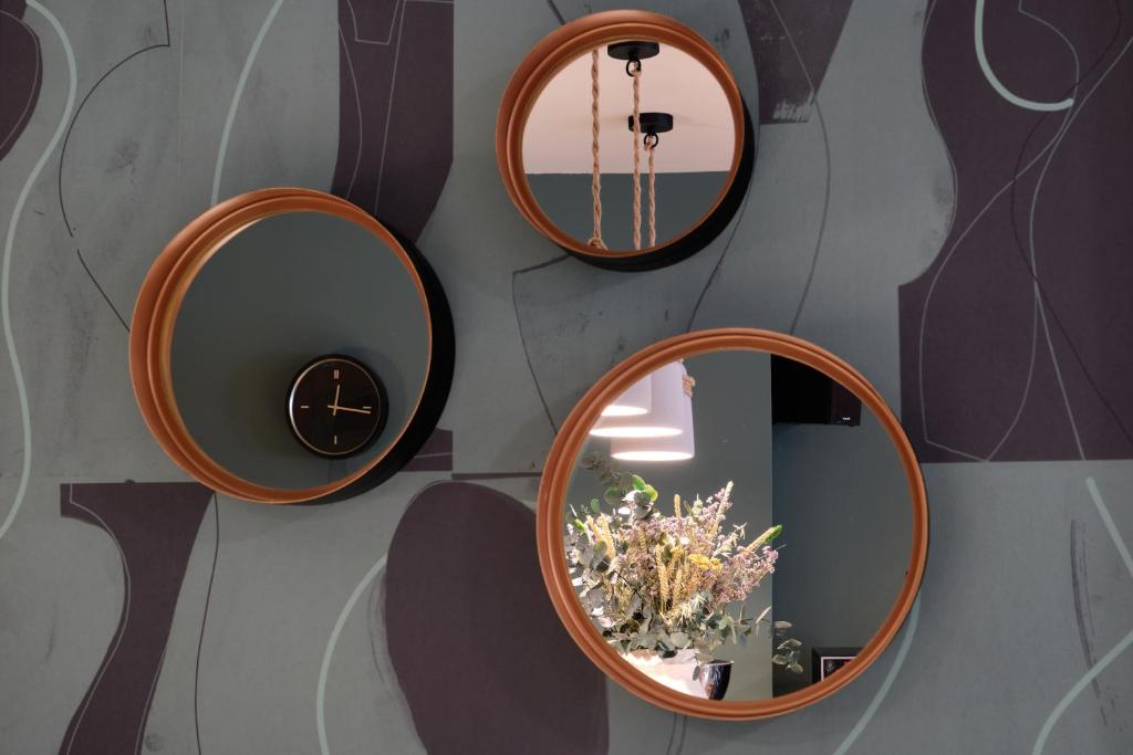 tre specchi rotondi su un muro con un vaso con fiori di Hotel Castro Real a Oviedo