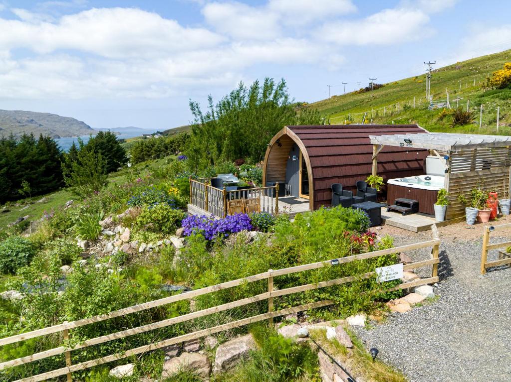 una pequeña cabaña de madera en una colina con flores en The Highland Bothies Glamping, en Ullapool