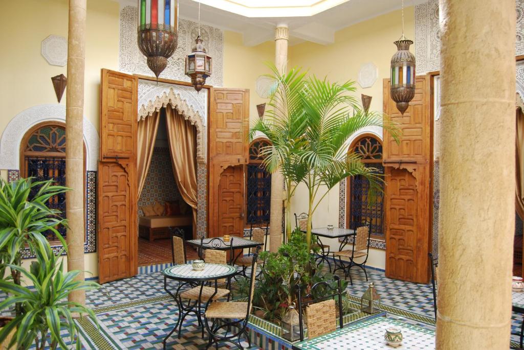 a lobby with tables and chairs and palm trees at Riad Dar Zouhour in Rabat