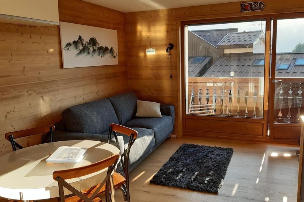 uma sala de estar com um sofá, uma mesa e uma janela em Les Carroz d'Arâches, joli studio plein centre. 