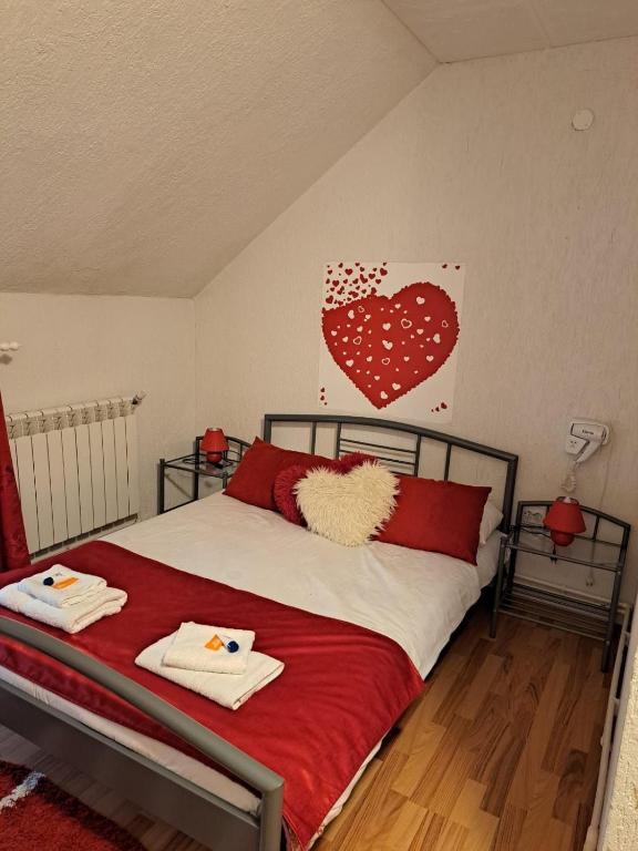 a bedroom with a bed with red pillows and a heart on the wall at CASA ARIAN in Haţeg