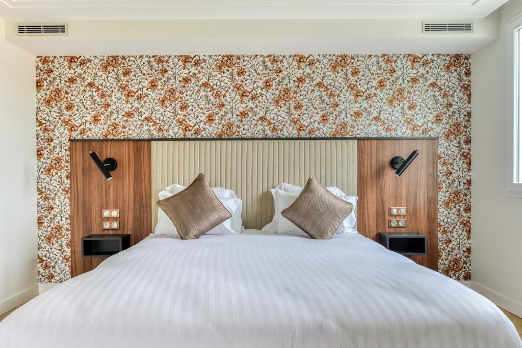 1 dormitorio con 1 cama blanca grande con cabecero de madera en Zenitude Hotel la Valadière, an Ascend Collection Hotel, en Montpellier