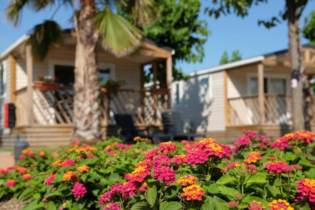 a house with a garden of flowers in front of it at Camping El Pinar in Blanes